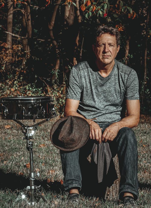 Calm male musician sitting near drum after performance in nature