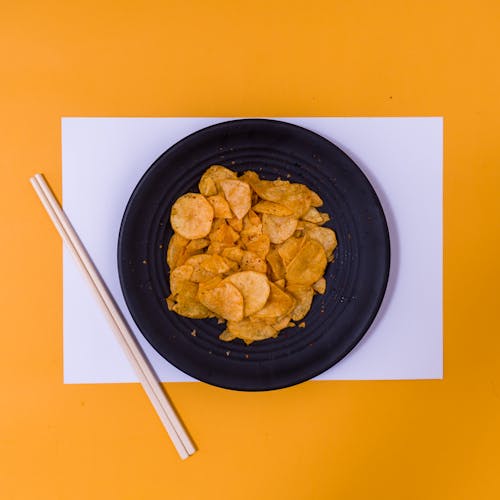 Free Potato Chips in Black Ceramic Bowl Beside Chopsticks Stock Photo