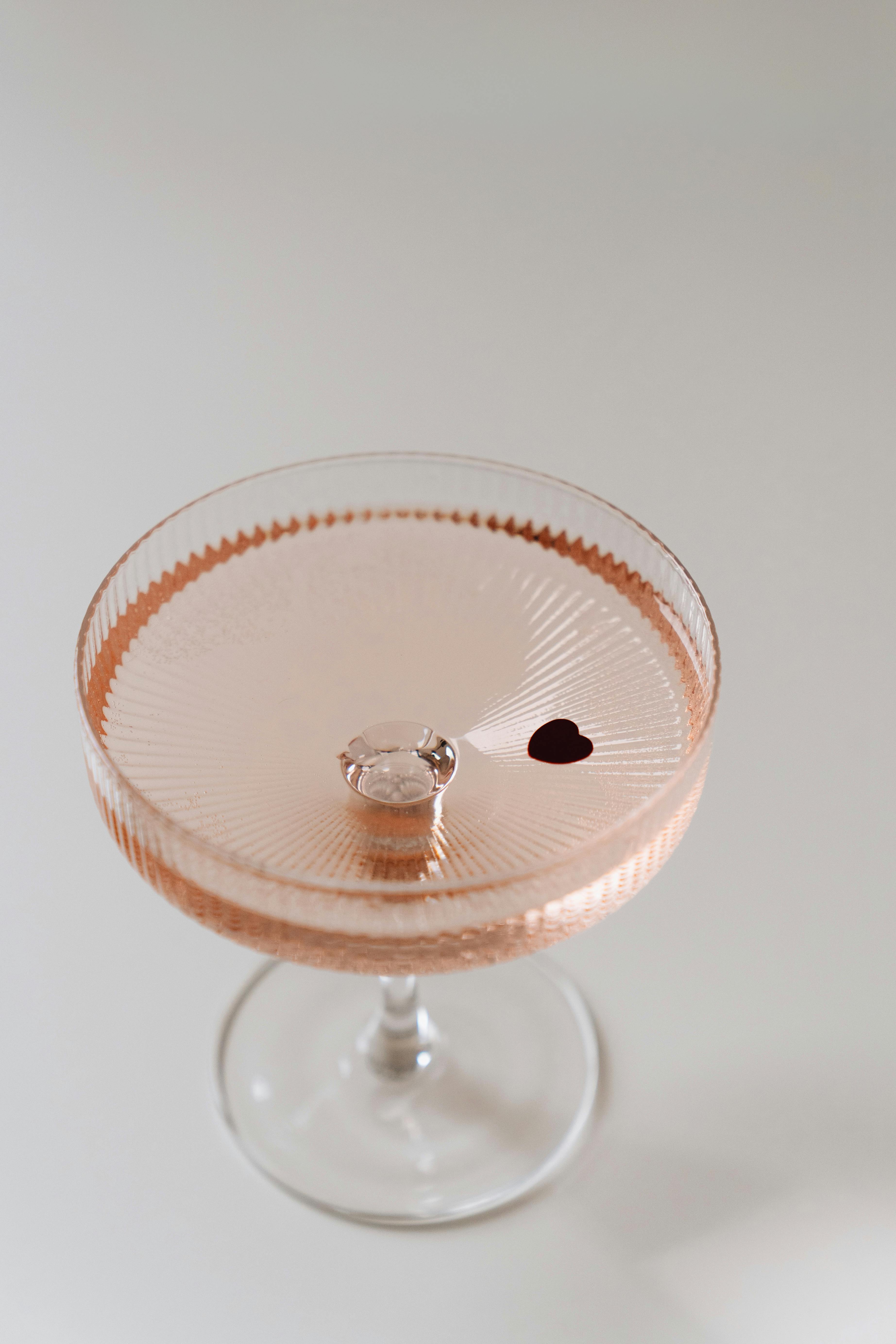 Elegant champagne glass with a diamond ring and heart decoration on a white background.