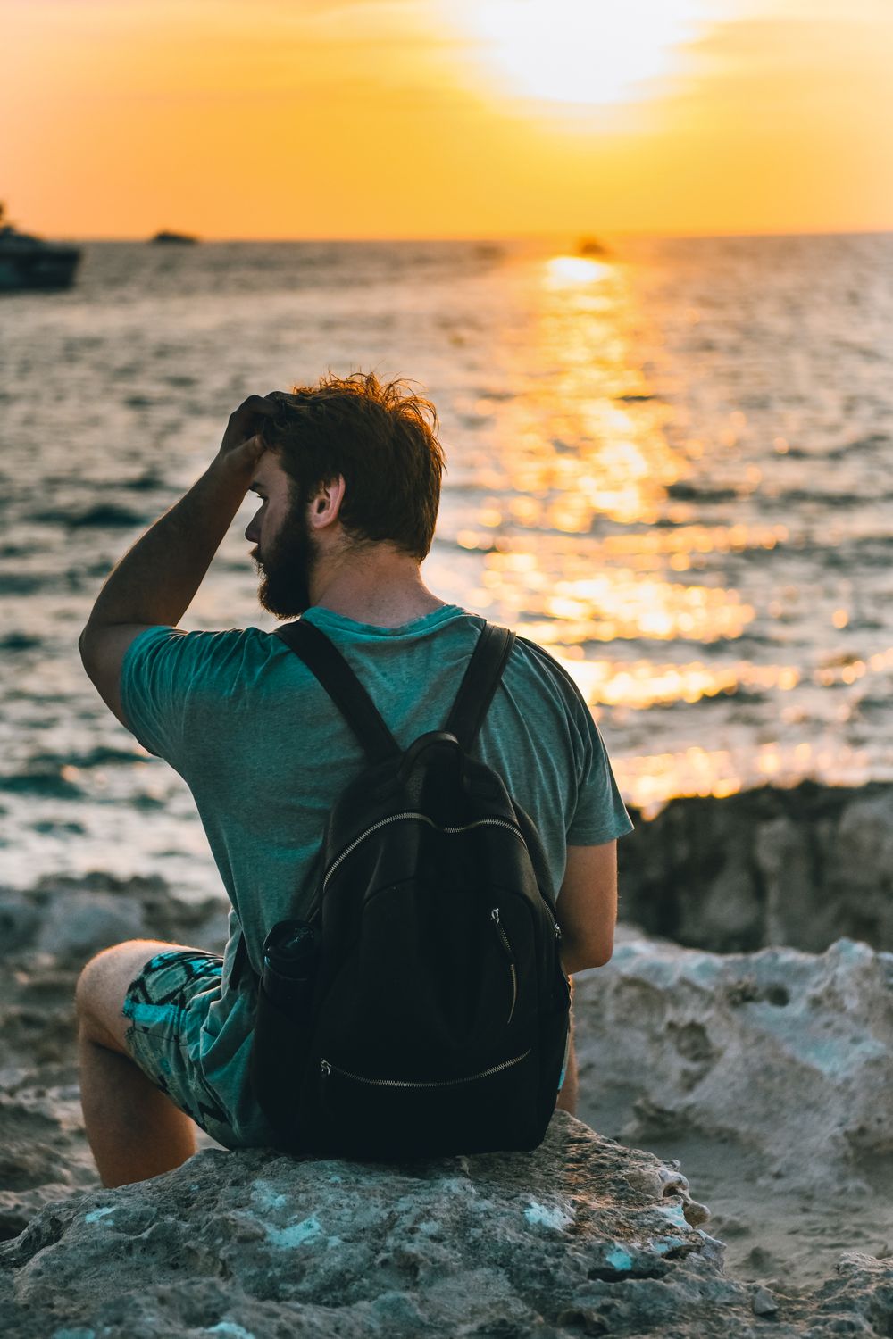 A Man Sitting on a Rock During Sunset · Free Stock Photo