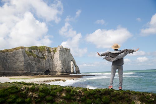 Faceless traveler on stony coast near sea