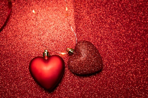 Top view of heart shaped decorations placed on red surface with bright glitters during holiday celebration on Saint Valentine day