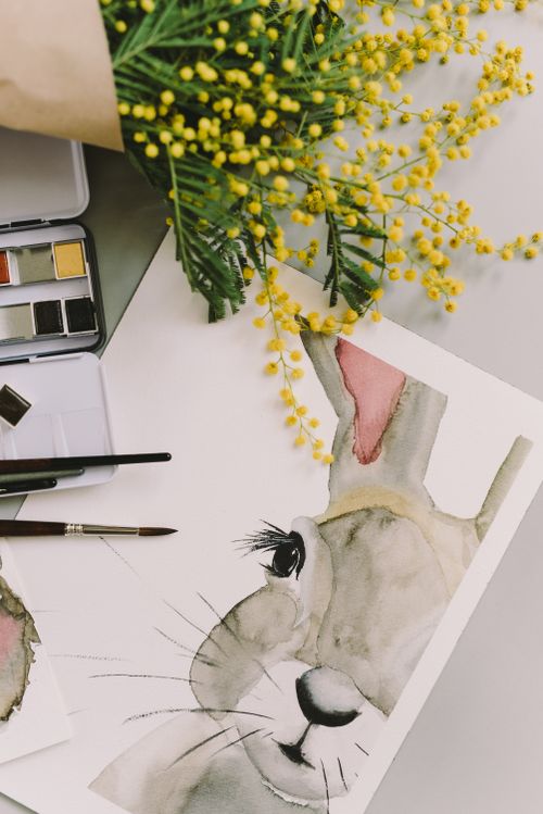 Free Watercolor painting of a rabbit surrounded by mimosa flowers, perfect for Easter or spring themes. Stock Photo