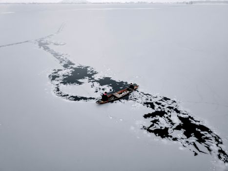 Men navigating a boat through icy waters on a frozen lake in Srinagar.