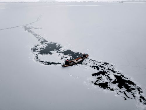 Free Men navigating a boat through icy waters on a frozen lake in Srinagar. Stock Photo