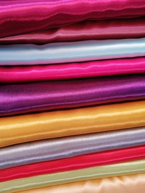 Nhiều lớp vải satin màu bạc, hồng, tím, vàng và tím nhạt xếp chồng lên nhau, mỗi lớp phản chiếu ánh sáng theo cách riêng