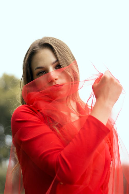 A Woman in red Ling Sleeve Shirt Holding a Red Sheer Fabric