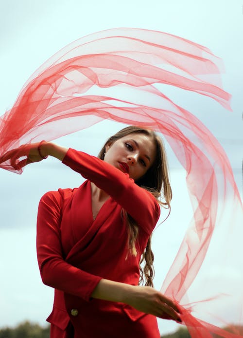 Photo of a Girl in a Red Top Waving a Red Sheer Fabric