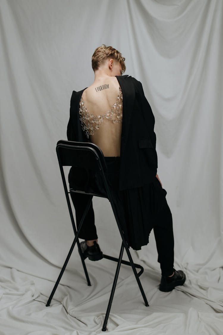 A Man Wearing Black Clothes Showing His Back With Tattoo