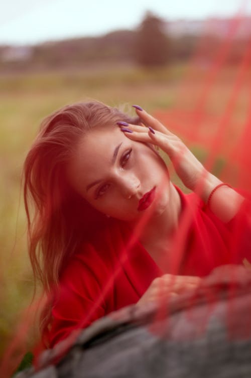 Portrait of a Woman in a Red Top Posing with Her Hand on Her Head