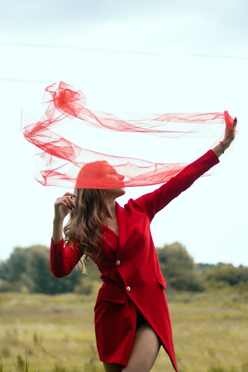 Woman in a Red Coat Posing with a Sheer Fabric