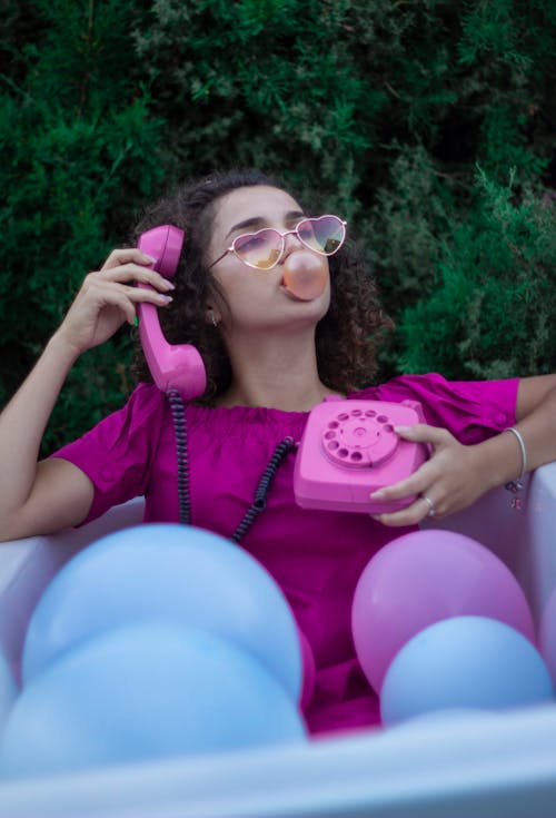 Woman in Purple Shirt with Sunglasses Playing with Bubble Gum 