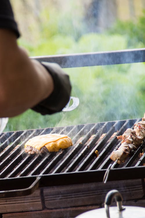 Free Person Grilling Hamburger and Skewer Stock Photo