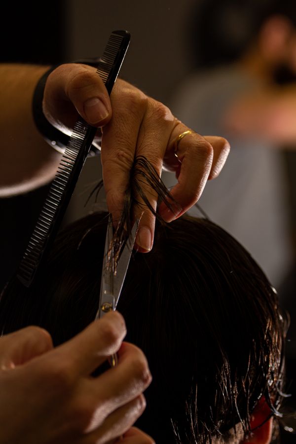 Close-up of a barber point-cutting hair with scissors and a comb