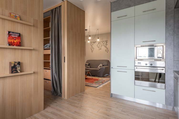 House With Cupboards In Kitchen Near Bookshelves And Living Room