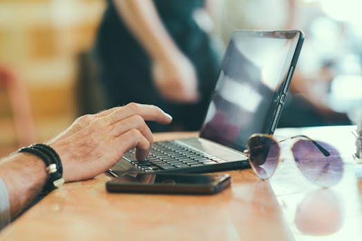Free stock photo of sunglasses, hand, smartphone, desk
