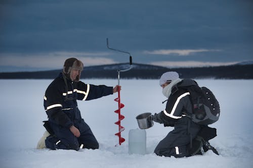 A Man and a Woman Drilling on Snow