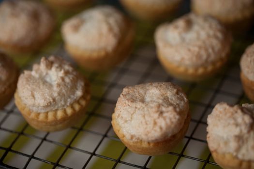 Freshly baked meringue-topped tarts on a cooling rack, showcasing homemade indulgence.