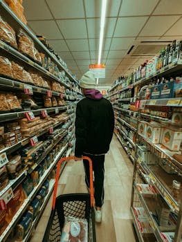 A shopper browsing aisles with products in a well-lit grocery store.