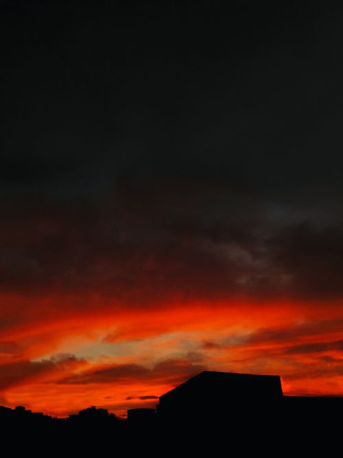 Free Capture of a vivid red sunset with silhouetted buildings, creating a striking contrast in the sky. Stock Photo