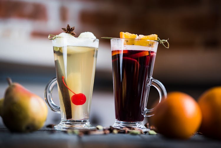 Glasses Of Spiced Wine Drinks With Fruit Slices On Skewers