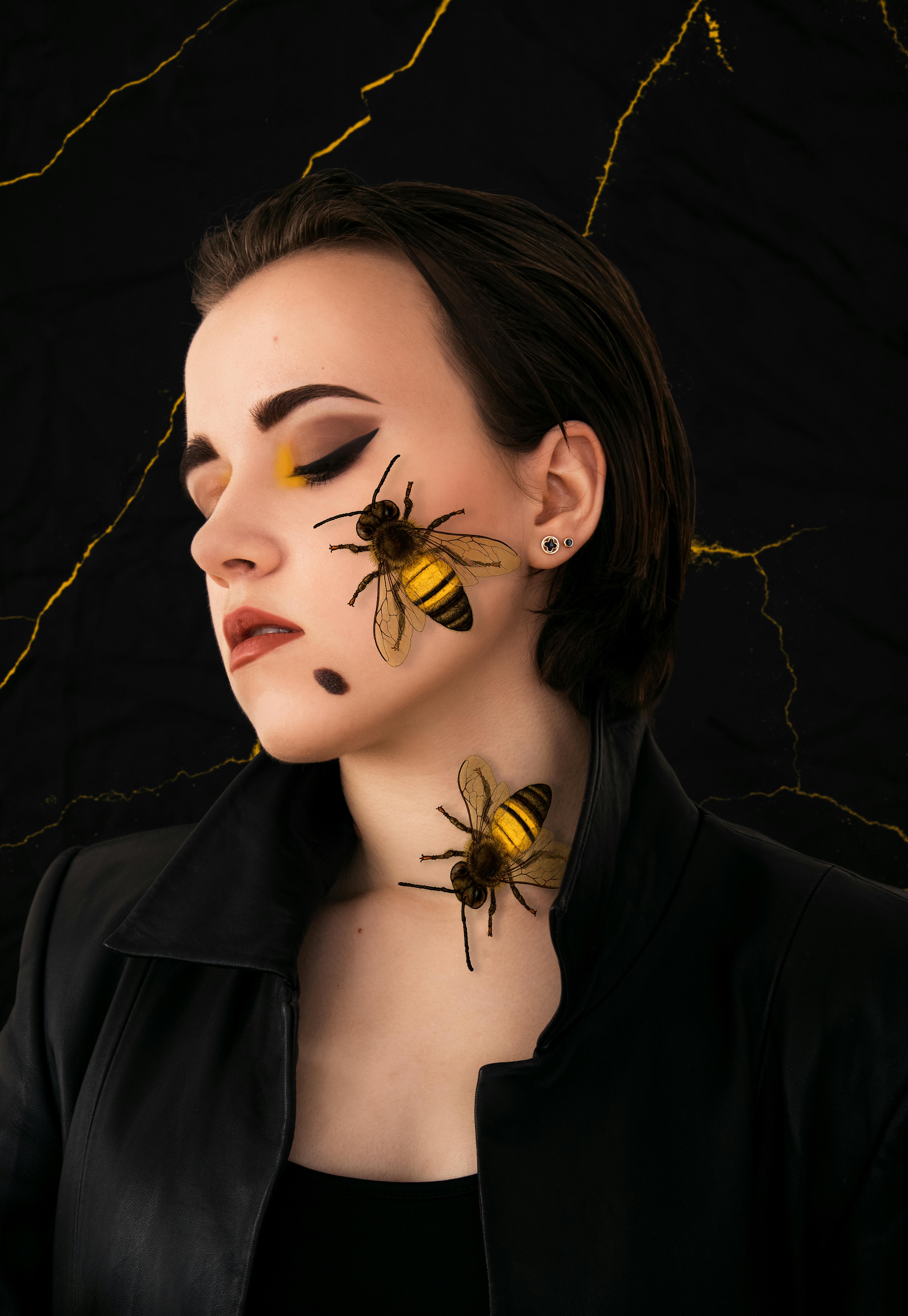 a woman in black jacket with yellow and black bees on her face and neck