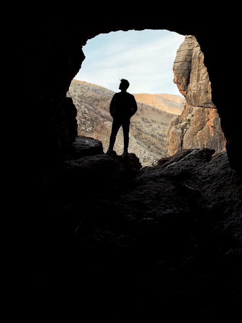 Free Man Standing Inside a Cave Stock Photo