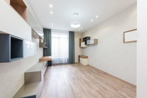 Minimalist design of modern room with cupboards placed against wall with mirror near window with curtain in apartment at home