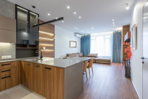 Free Interior of spacious flat with wooden cabinets in modern kitchen placed near table and comfortable couch near window at home Stock Photo