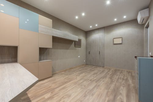 Interior of spacious light room with cabinets and closet placed in modern apartment with glowing lights on ceiling at home