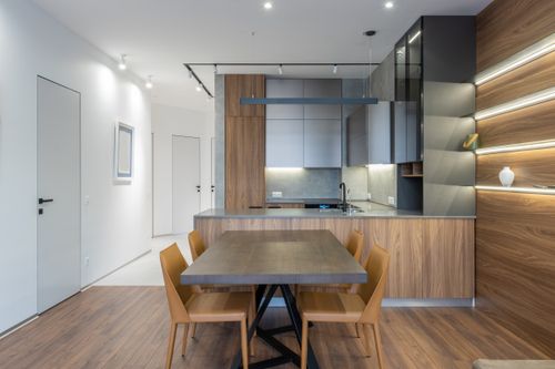 Free Table and chairs placed near contemporary kitchen with cupboards and sink in stylish apartment with white corridor and light decoration Stock Photo