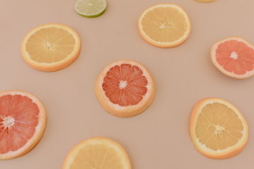 Free A vibrant selection of sliced citrus fruits including grapefruit, orange, and lime on a neutral background. Stock Photo