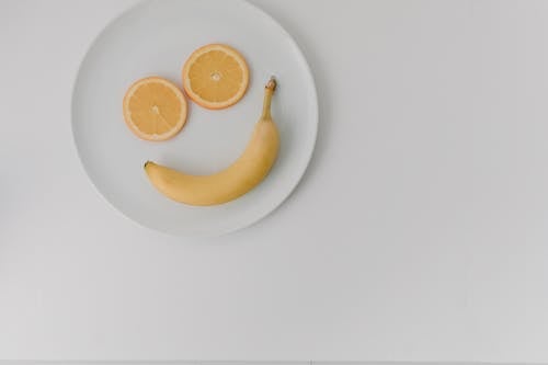 Yellow Banana Fruit and Slices of Orange on White Ceramic Plate