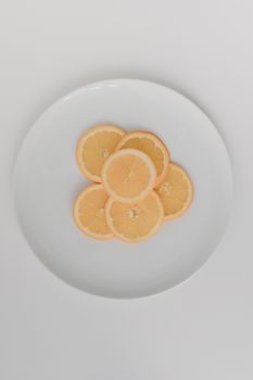 Top view of fresh orange slices arranged on a white ceramic plate.