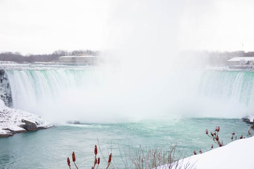 Winter view of Niagara Falls with cascading waters and a snowy landscape.