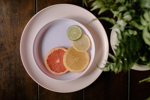 Sliced colorful citrus fruits placed on plate on wooden table