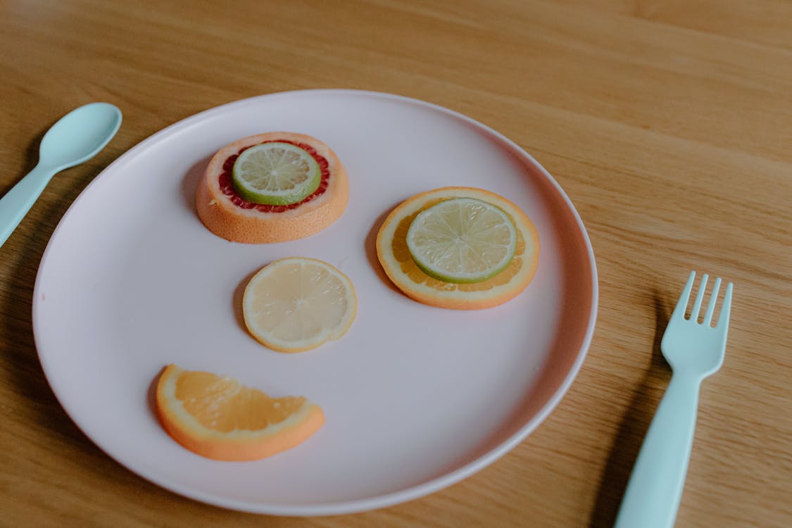 Multicolored citrus fruit creating funny face on plastic plate
