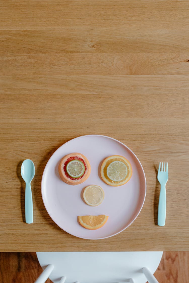 Funny Face Created By Assorted Sliced Fruits On Plastic Plate