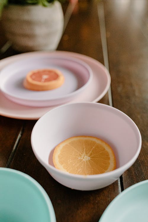 Plate and bowl with slices of healthy orange and grapefruit