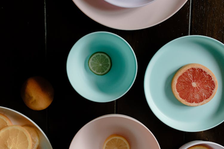 Sliced Citrus Fruits In Plastic Bowls And Plate