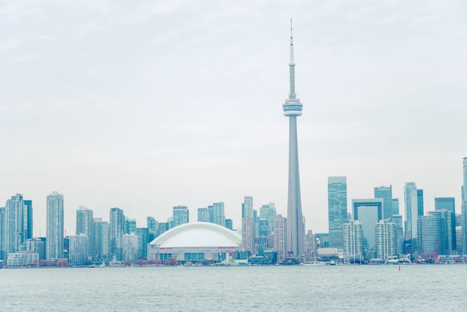 Panoramic view of Toronto skyline featuring the iconic CN Tower against a daytime sky.