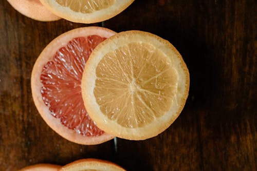 Top view of texture of pulp of sliced grapefruit and lemon on wooden table