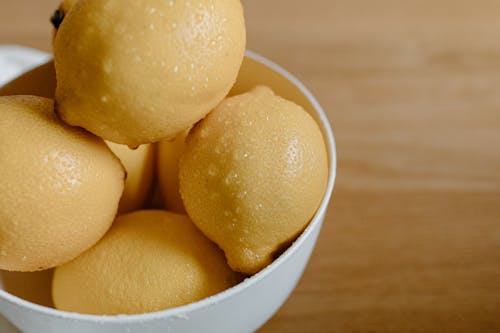 From above of clean lemons with water drops in bowl on table in kitchen