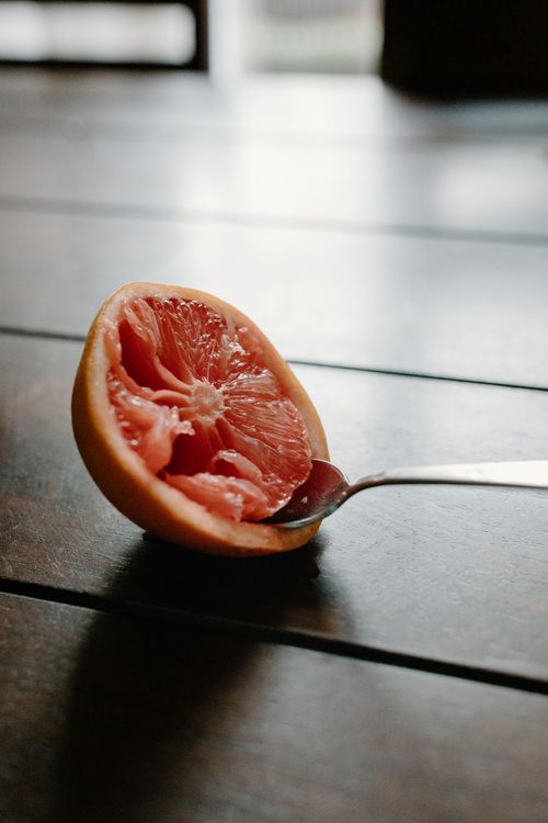 Free From above of fresh juicy grapefruit with spoon in pulp placed on wooden table Stock Photo