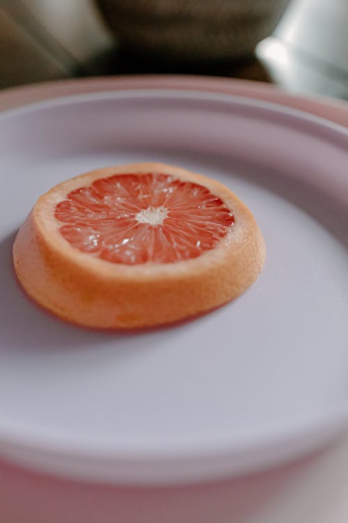 High angle of piece of cut juicy exotic grapefruit placed on white plate in daylight