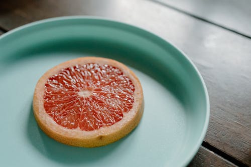 Sliced juicy grapefruit on plate on wooden table