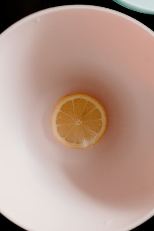 Top view of ripe yellow half of lemon placed in white bowl for breakfast