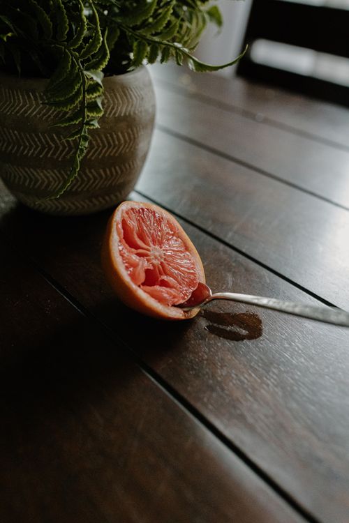 Free From above of ripe juicy grapefruit with spoon on table with green potted plant Stock Photo