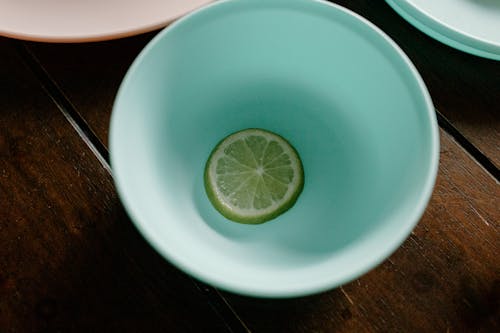 Sliced lime in bowl with water on table near dinnerware