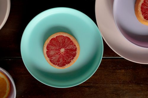 Free Top view of wooden table with ceramic plates with sliced ripe red grapefruits in light place Stock Photo